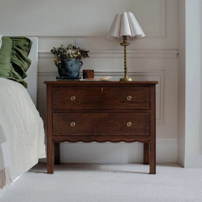 Elegant wooden nightstand with two drawers, decorative handles, and scalloped edge design